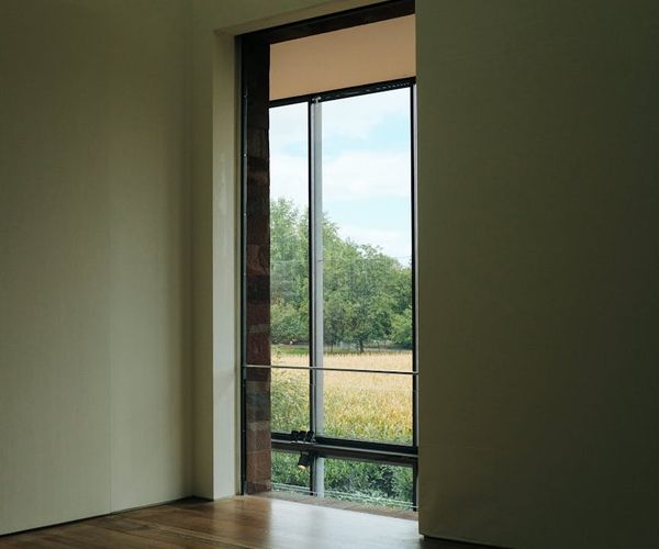 A clean, modern, and empty fitness studio with wooden floors and large windows.