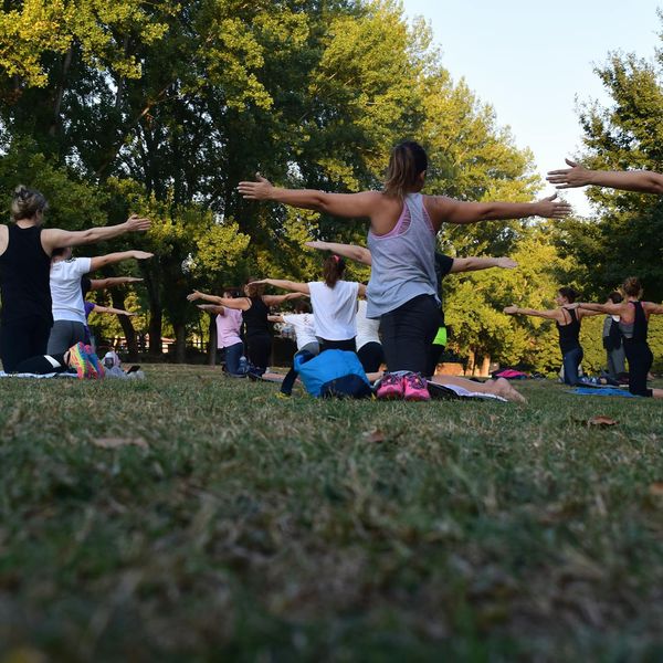 A diverse group of people smiling and stretching in a bright, modern fitness space.